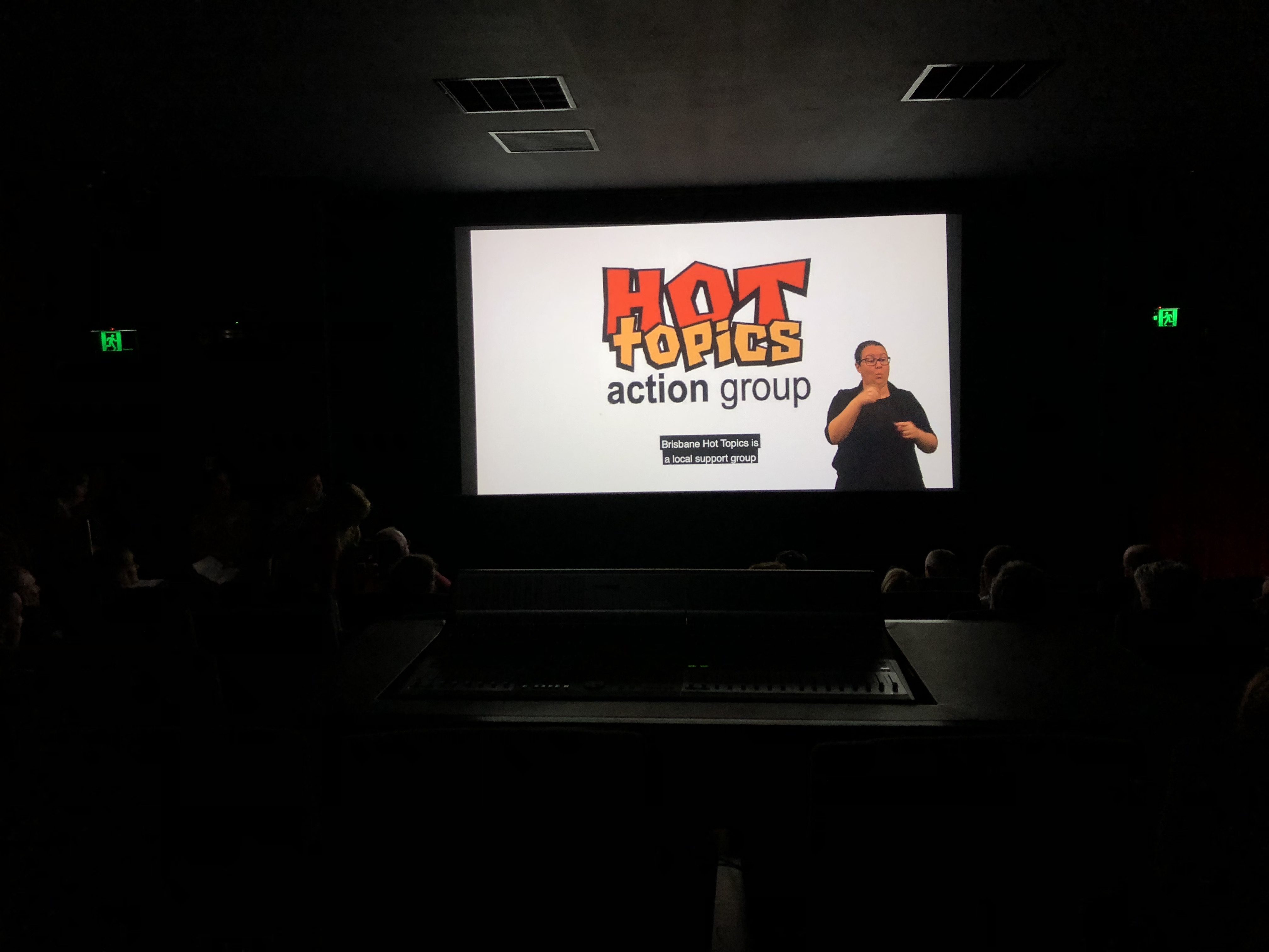darkened room with overhead of Brisbane Hot Topics logo