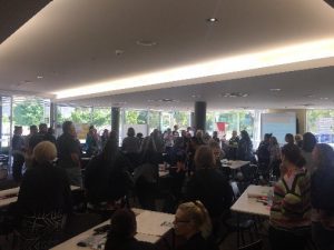 About 100 people gathered in a room chatting to each other