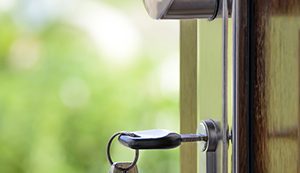 A key that is in a lock on a front door. There is an extra key hanging from the keychain.