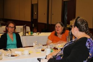 Elisha Matthews, Donna Best and Wendy Lovelace in group discussions, sitting around a table.