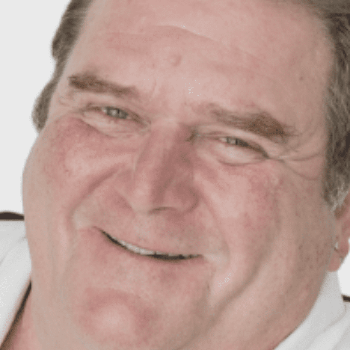 A close up photo of a man smiling.