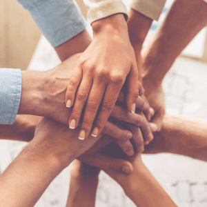 5 peoples sets of hands placed on top of one each other.