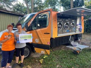2 ladies standing by an orange van. They are holding a sign that say targeted outreach.