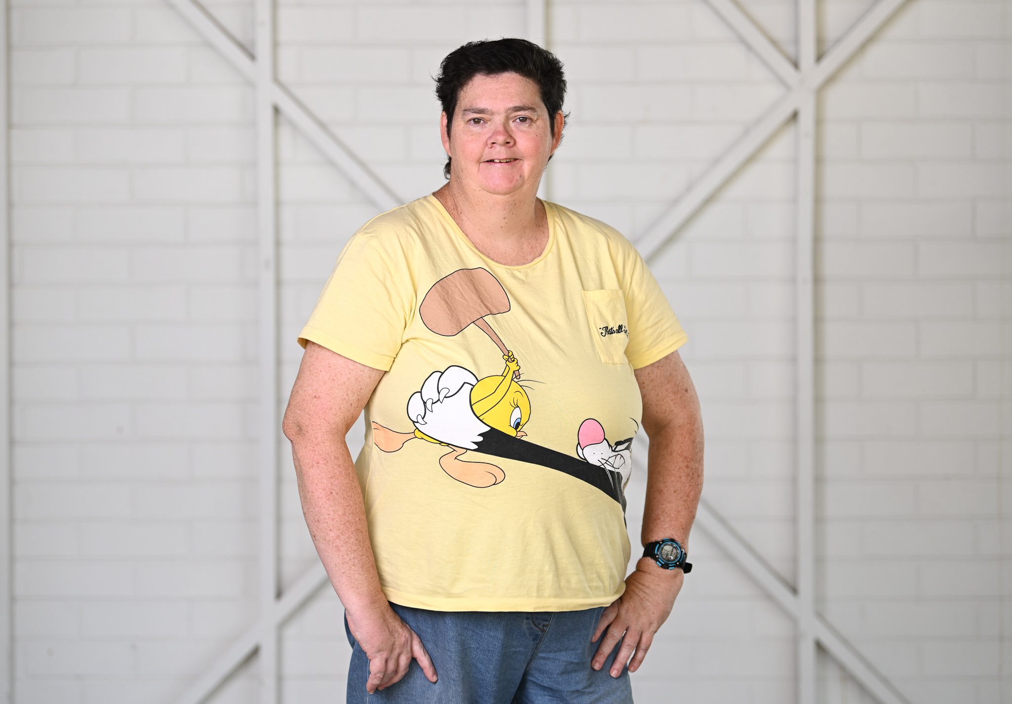 A woman with brown short hair, wearing a pale yellow tshirt and smiling at the camera.