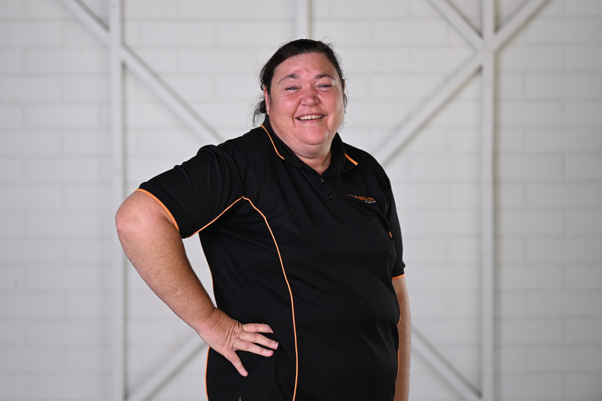 A woman with dark brown hair, wearing a black polo shirt and smiling at the camera.