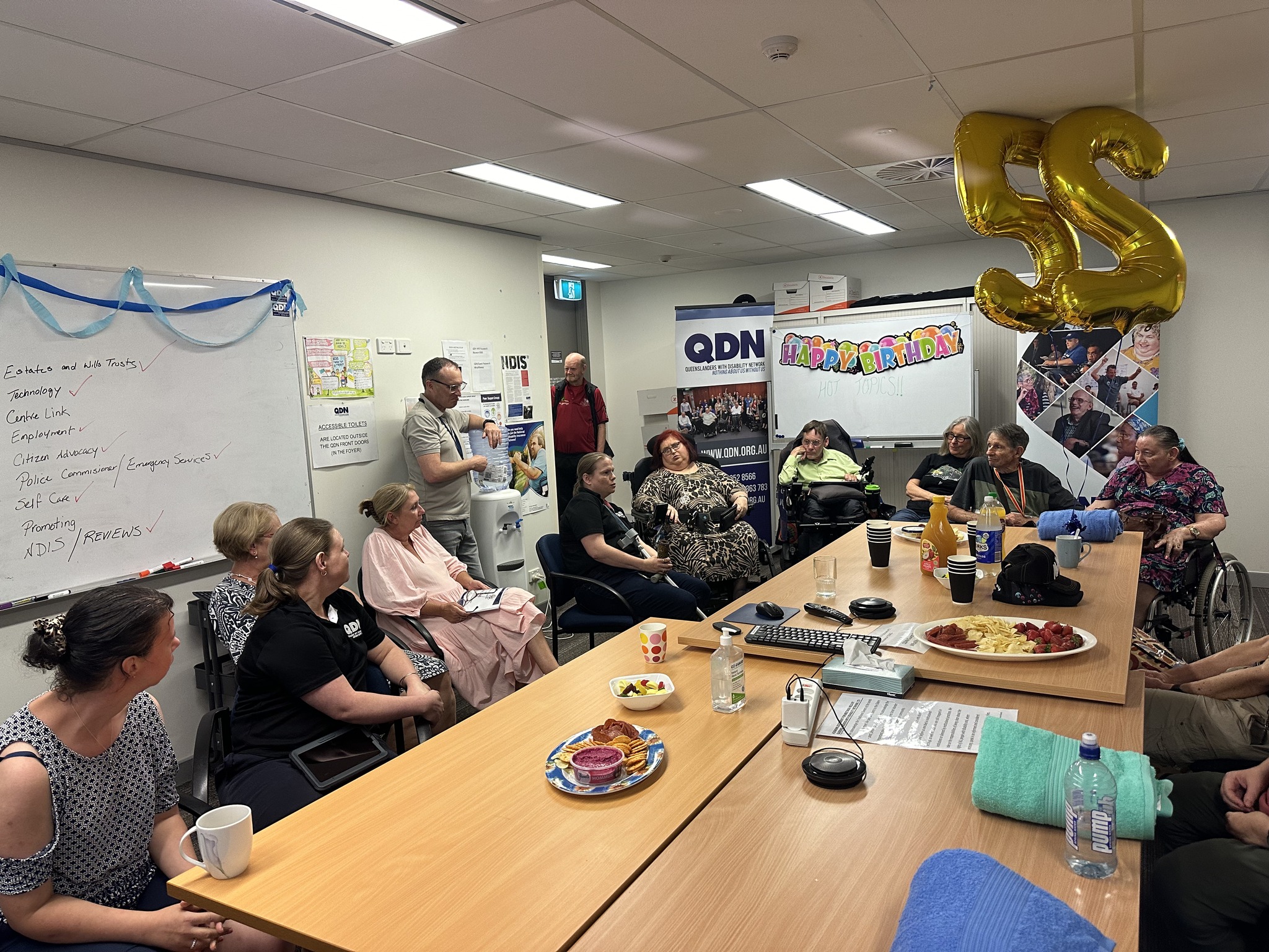 Photo group of people with disability sitting around the table. It's a day to celebrate the group longevity. 